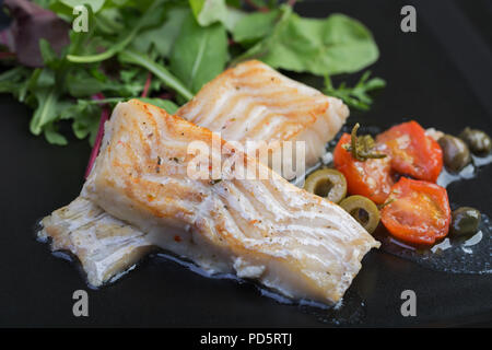 Filetti di merluzzo con olive e capperi sulla piastra nera / cucina mediterranea Foto Stock