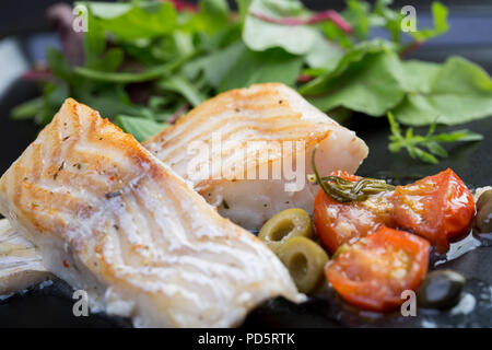 Filetti di merluzzo con olive e capperi sulla piastra nera / cucina mediterranea Foto Stock