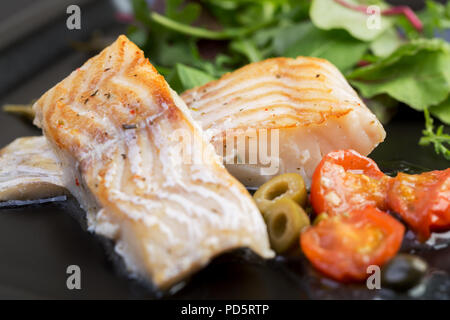 Filetti di merluzzo con olive e capperi sulla piastra nera / cucina mediterranea Foto Stock