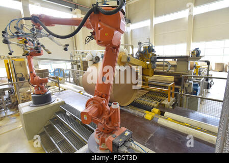 Robot industriale in un mulino di carta - automazione in un impianto moderno - riciclaggio di rifiuti di carta Foto Stock