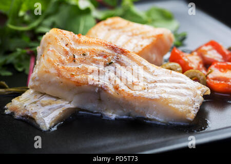 Filetti di merluzzo con olive e capperi sulla piastra nera / cucina mediterranea Foto Stock