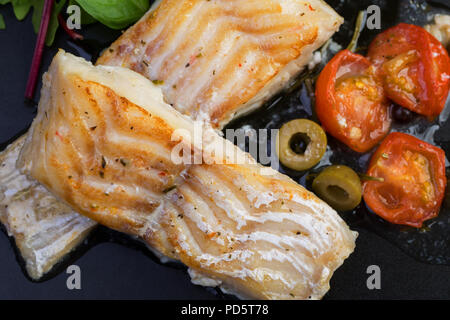 Filetti di merluzzo con olive e capperi sulla piastra nera / cucina mediterranea Foto Stock