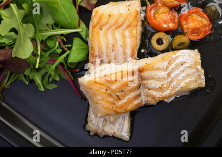 Filetti di merluzzo con olive e capperi sulla piastra nera / cucina mediterranea Foto Stock