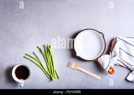 Stoviglie utensili da cucina, cucina sfondo con ingredienti, frypan, asparagi, tazza di caffè preparato per la colazione, vista dall'alto, copia dello spazio. Foto Stock