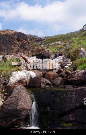 Masterizzazione di montagna che scorre verso il basso per Loch Diabaigas Airde attraverso arenaria Torridonian da wildfire bruciato Bracken. Torridon, Scotland, Regno Unito. Foto Stock
