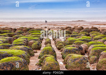 Coppia distanti a piedi sulla spiaggia a Hunstanton, Norfolk, Inghilterra, con la bassa marea, d'inverno. Foto Stock