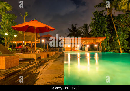 Hotel nella giungla tropicale. Notte piscina. Le palme, ombrelloni, lettini e bar. Nessuno Foto Stock