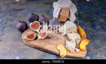 Fichi maturi, nobile formaggio con stampo, pesche su un tagliere. Foto Stock