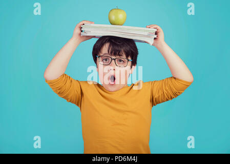 Ragazzino con mela verde e libri su sfondo blu Foto Stock