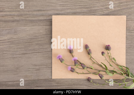 Viola con fiori di campo artigianali fatti a mano notebook sul vecchio grunge sfondo di legno. Vista dall'alto. In stile minimalista mockup. Foto Stock