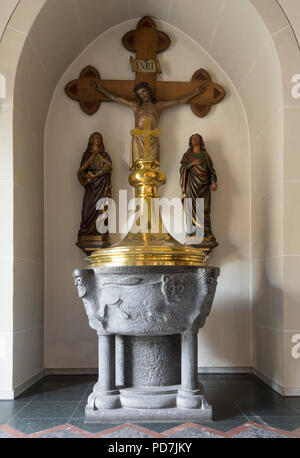 Romanisches Taufbecken in der Vorhalle, dahinter Kreuzigungsgruppe aus dem 19. Jahrhundert Foto Stock