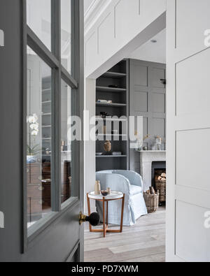 Vista attraverso il vetro aperto lo sportello con pannelli di salotto a pianta aperta con boiserie e sfregata pavimenti in legno. Foto Stock