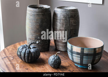 Due vasi di legno dal Sud Africa sono visualizzati su un piccolo tavolo in salotto con zucche essiccate e una ciotola da anta. Foto Stock