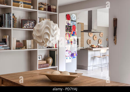 Carta luce pendente da Skandium pende al di sopra di una quercia tavolo da pranzo. Sullo sfondo la cucina è visibile attraverso un'arcata quadrata Foto Stock