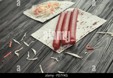 Salsicce affumicate, cavolo e pane pita isolato su sfondo di legno. Foto Stock