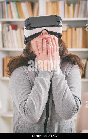 Donna che utilizza la realtà virtuale auricolare per combattere il suo fobie o paure a casa Foto Stock