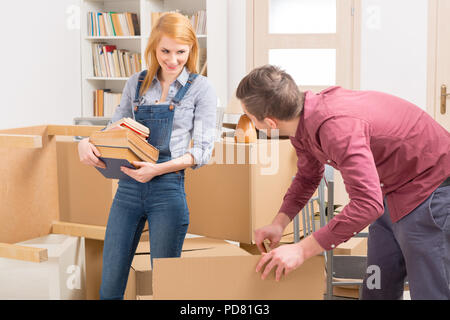 Felice coppia giovane disimballaggio caselle nella loro nuova casa Foto Stock