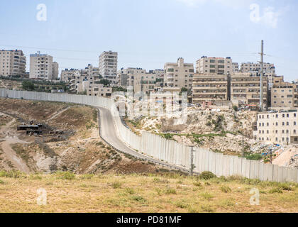 Vista dal Mar Morto a Gerusalemme di strada nella West Bank area palestinese della barriera di separazione, qui un alto muro in cemento armato, e appartamento israeliano Foto Stock