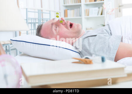 Il russamento uomo nel letto con un panno agganciare il suo naso Foto Stock
