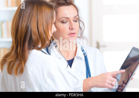 Due donne medici cercando su tablet pc e discutere di risultato delle prove Foto Stock