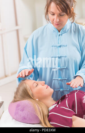 Professional guaritore Reiki facendo trattamento reiki alla giovane donna Foto Stock