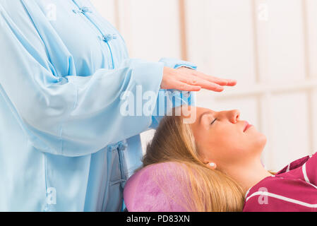 Professional guaritore Reiki facendo trattamento reiki alla giovane donna Foto Stock