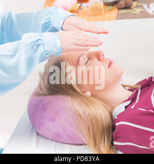 Professional guaritore Reiki facendo trattamento reiki alla giovane donna Foto Stock