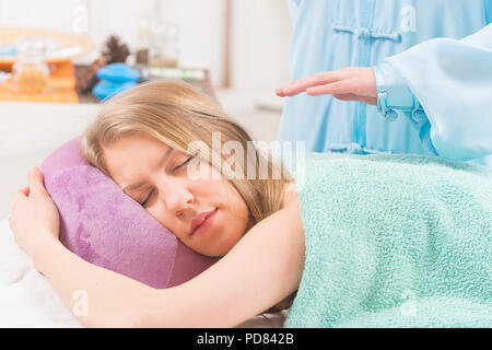 Professional guaritore Reiki facendo trattamento reiki alla giovane donna Foto Stock