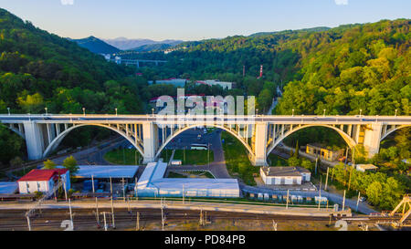 Drone Vista del viadotto Matsesta e la ferrovia sullo sfondo di montagne con una densa foresta nella soleggiata giornata estiva, Sochi, Russia Foto Stock