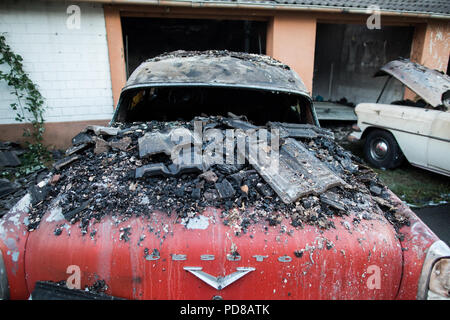 Siegburg Germania. 07 Ago, 2018. completamente bruciato auto d'epoca in piedi di fronte a un bruciato garage. Numerose case hanno preso fuoco a causa di un incendio direttamente sul Cologne-Frankfurt importante linea ferroviaria. Credito: Marcel Kusch/dpa/Alamy Live News Foto Stock