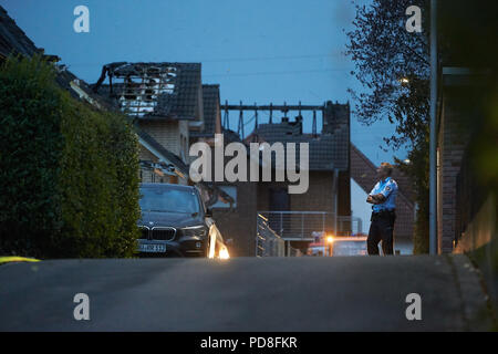 Siegburg Germania. 08 Ago, 2018. Un poliziotto fissa bruciate le case dopo il fuoco su un terrapieno della linea di ghiaccio vicino a Siegburg. Numerose persone sono state ferite nel fuoco. Credito: Thomas Frey/dpa/Alamy Live News Foto Stock