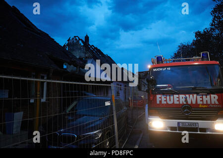 Siegburg Germania. 08 Ago, 2018. Vigili del fuoco a piedi accanto a bruciate le case dopo il fuoco su un terrapieno della linea di ghiaccio vicino a Siegburg. Numerose persone sono state ferite nel fuoco. Credito: Thomas Frey/dpa/Alamy Live News Foto Stock