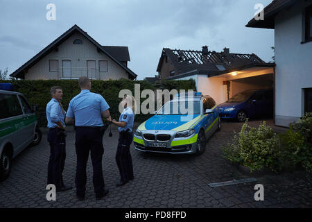 Siegburg Germania. 08 Ago, 2018. Forze di polizia sono in piedi accanto a bruciato case dopo un incendio su un terrapieno della linea di ghiaccio vicino a Siegburg. Numerose persone sono state ferite nel fuoco. Credito: Thomas Frey/dpa/Alamy Live News Foto Stock