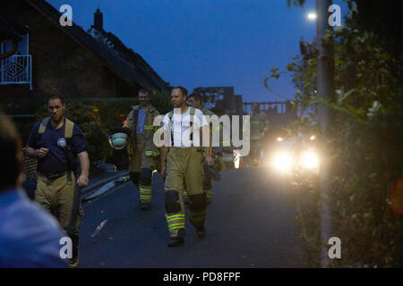 Siegburg Germania. 08 Ago, 2018. Vigili del fuoco a piedi accanto a bruciate le case dopo il fuoco su un terrapieno della linea di ghiaccio vicino a Siegburg. Numerose persone sono state ferite nel fuoco. Credito: Thomas Frey/dpa/Alamy Live News Foto Stock