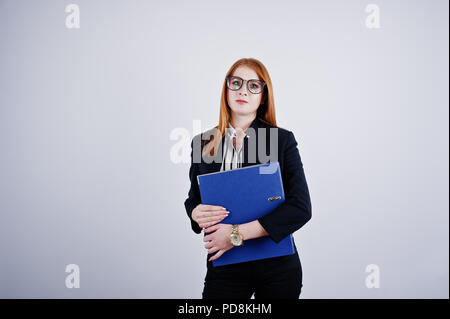 Ritratto di una imprenditrice redheaded indossando camicia a righe e una giacca con una cartella di blu. Foto Stock