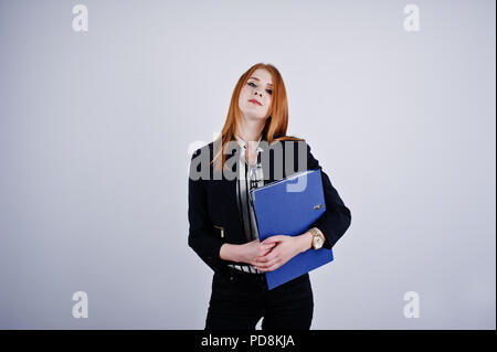 Ritratto di una imprenditrice redheaded indossando camicia a righe e una giacca con una cartella di blu. Foto Stock