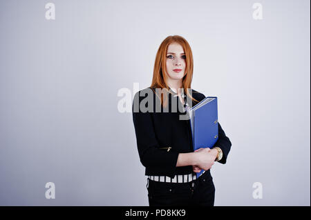 Ritratto di una imprenditrice redheaded indossando camicia a righe e una giacca con una cartella di blu. Foto Stock