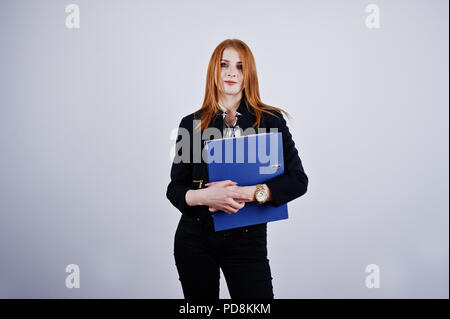 Ritratto di una imprenditrice redheaded indossando camicia a righe e una giacca con una cartella di blu. Foto Stock