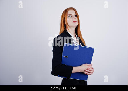 Ritratto di una imprenditrice redheaded indossando camicia a righe e una giacca con una cartella di blu. Foto Stock