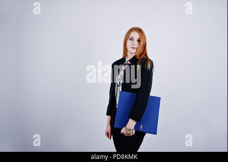 Ritratto di una imprenditrice redheaded indossando camicia a righe e una giacca con una cartella di blu. Foto Stock