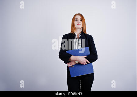 Ritratto di una imprenditrice redheaded indossando camicia a righe e una giacca con una cartella di blu. Foto Stock