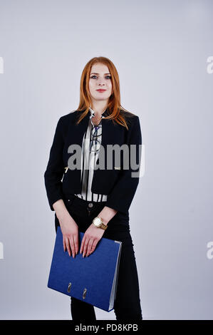 Ritratto di una imprenditrice redheaded indossando camicia a righe e una giacca con una cartella di blu. Foto Stock