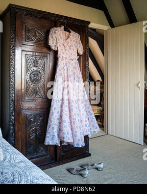 1930s Vintage dress appeso su antichi in legno di quercia intagliato armadio Foto Stock