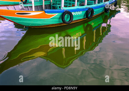 Riflessioni da quella del porto di colorate barche in Hoi An centro turistico acque. La città antica, VN Foto Stock