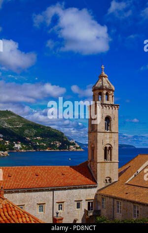 La torre campanaria del monastero domenicano nella città vecchia di Dubrovnik, Croazia con parte del blu del mare Adriatico e una montagna Foto Stock