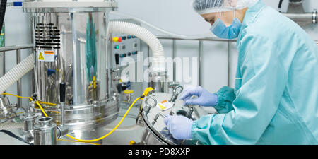 Fabbrica farmaceutica donna lavoratrice in abbigliamento protettivo di funzionamento della linea di produzione in ambiente sterile Foto Stock