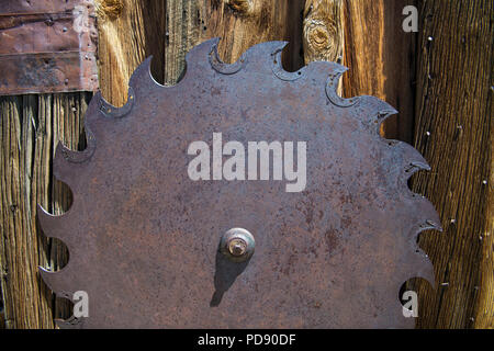 Arrugginita la lama contro un rustico di legno stagionato background in un abbandonato mulino di legname nella storica città fantasma di Bodie, California Foto Stock