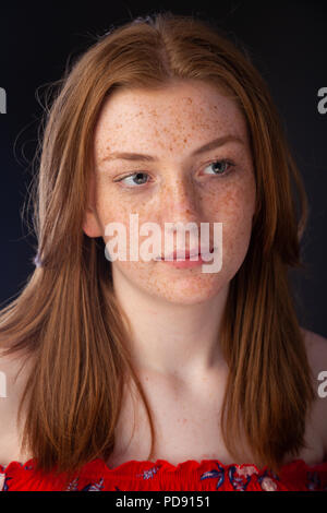 Ritratto di una bella ragazza con i capelli rossi e le lentiggini guardando lontano dalla telecamera. Foto Stock