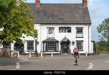 Bracci Carden un sedicesimo secolo Coaching Inn at Tilson Malpas, Cheshire, Inghilterra, Regno Unito. Vista esterna con un ciclista di passaggio, Foto Stock