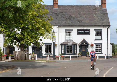 Bracci Carden un sedicesimo secolo Coaching Inn at Tilson Malpas, Cheshire, Inghilterra, Regno Unito. Vista esterna con un ciclista di passaggio, Foto Stock